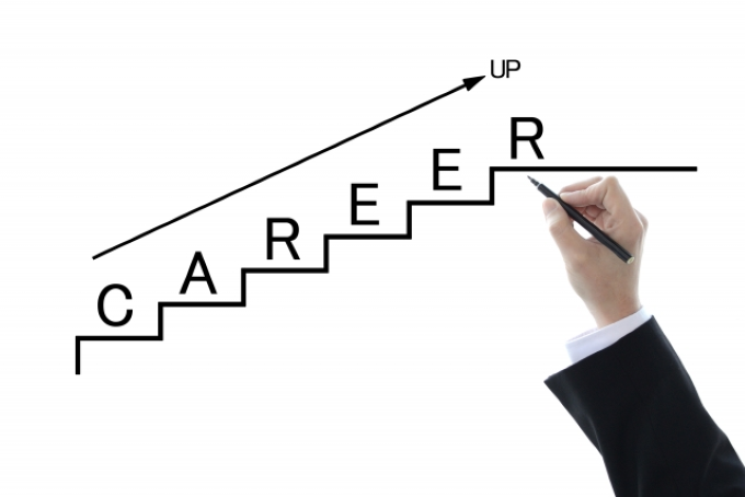 階段状に「CAREER」と書かれた図を右上に向かって手書きで描くビジネスマンの手。キャリアアップ・年収アップを象徴するイメージ。