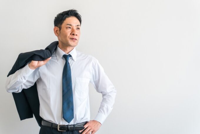 スーツの上着を肩にかけて前を見据える40代営業マンのイメージ