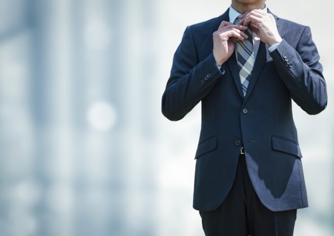 スーツ姿の男性がネクタイを整えている様子。営業経験がある50代が面接や新たな挑戦に向けて身だしなみを整えるイメージ。