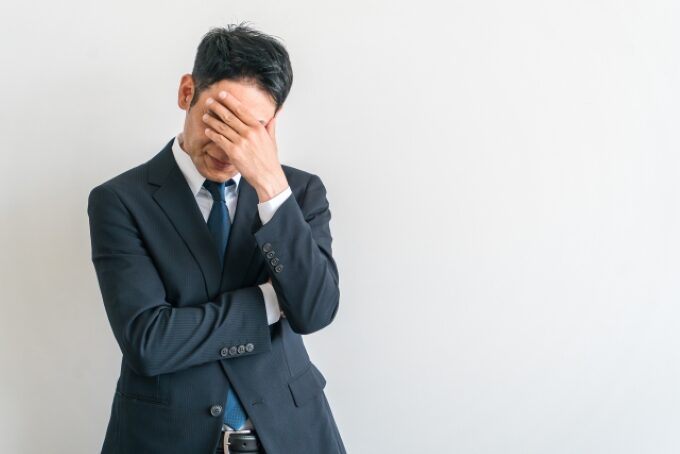 営業職への転職に不安を感じて悩むスーツ姿の中年男性のイメージ