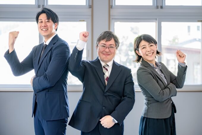 職場で活躍する営業チームの笑顔と自信を表すポーズをとるビジネスパーソンの画像